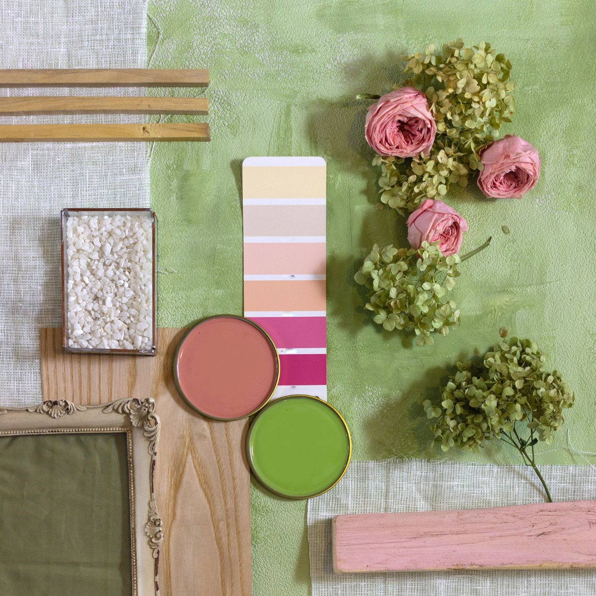 Color swatches and flowers on a green surface with a wooden frame and decorative elements.