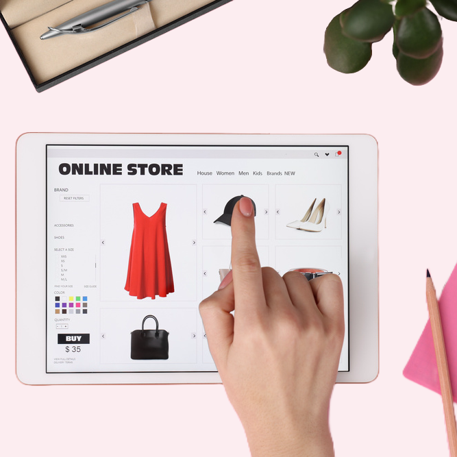 Hand interacting with a digital tablet displaying an online store with clothing items.